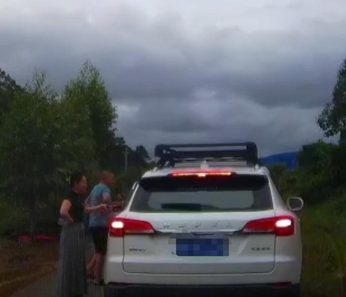 奔驰车上的男女下车和“平头哥”沟通让路,女司机左手中疑拿着一物品。